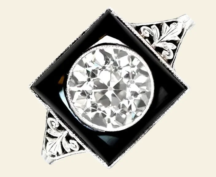 Notice the way the buffed onyx accentuates the bezel-set old European-cut diamond in the center of this 1920s-era Art Deco engagement ring. Offered by Estate Diamond Jewelry.